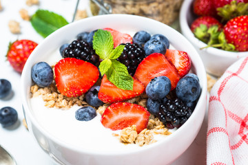 Greek yogurt granola with fresh berries on white table.