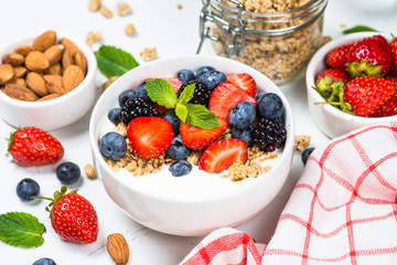 Greek yogurt granola with fresh berries on white table.