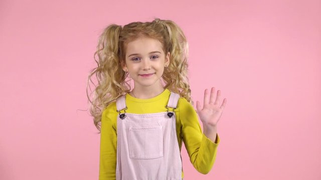 Pretty young girl is waving hello with her hand. Slow motion