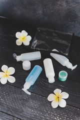 set of lotions and moisturizers popping out of transparent pouch surrounded by flowers