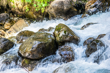 Naklejka na ściany i meble the water of the stormy mountain river flowing among stones and boulders