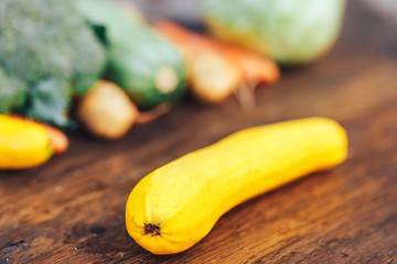 fresh salubrious colourful vegetables on wooden background, squash in focus, potatoes, carrots, broccoli, zucchini unfocused, selected focus