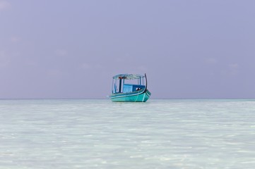 Ari Atoll, Maldives - 25 December 2018: A maldivian sailor is fishing on his blue boat called 'dhoni'