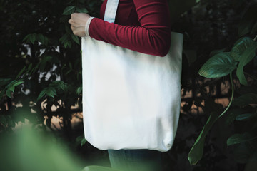 Girl is holding bag canvas fabric for mockup blank template on nature background.  global warming...