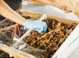 Female seller's hand picking up dried date from box