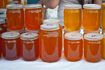 Lots of assorted honey on the table. Jars of sweets are sold at the fair.