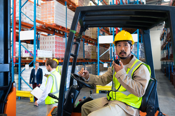 Male worker talking on walkie-talkie while driving forklift in warehouse © WavebreakMediaMicro
