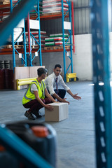 Male staff giving training to female staff in warehouse