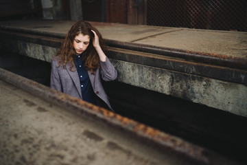 Young beautiful caucasian woman walking in old town. Female art portrait. Stylish girl with long curly red hair.