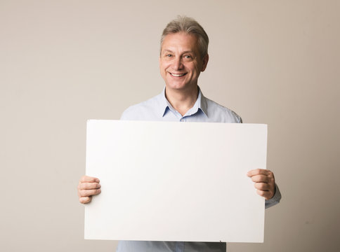 Happy mature man with blank advertising board