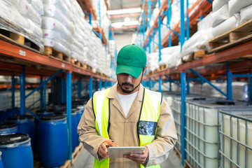 Male worker checking stocks on digital tablet in warehouse