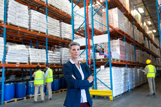 Female manager standing with arms crossed and looking at camera in warehouse