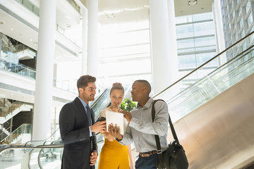 Diverse young business people with tablet talking in a modern atrium