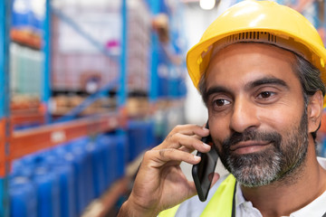 Male worker talking on mobile phone in warehouse