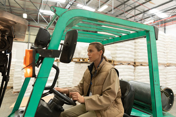 Naklejka premium Female worker driving forklift in warehouse
