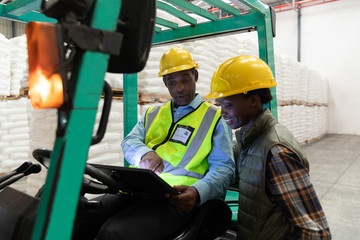Male and female worker discussing over digital tablet in warehouse