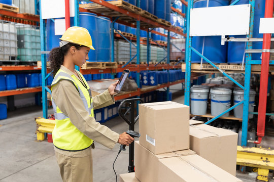 Female Worker Scanning Package With Barcode Scanner While Using Digital Tablet In Warehouse