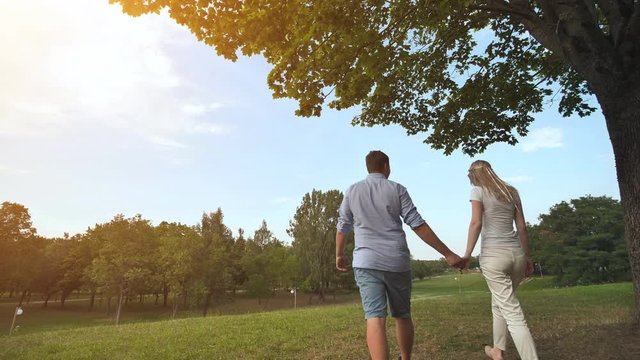 A guy and a girl walk in the park on a summer day