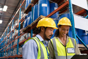Male and female worker discussing on clipboard in warehouse