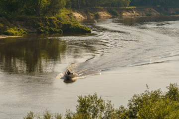 riverbank and a motor boat goes on the water