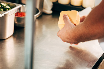cropped view of cook holding cheese at workplace