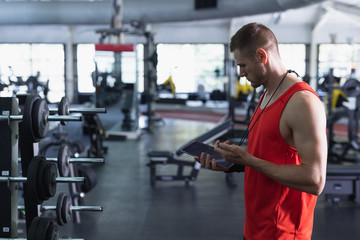Fototapeta na wymiar Male trainer using digital tablet in fitness center