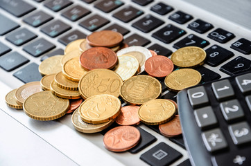 coins on laptop keyboard and calculator close-up. Business concept.