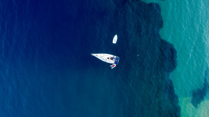 Aerial view of tropical island beach holiday yacht on blue reef ocean . Aerial drone bird's eye top view of traditional fishing boat in port of Turkey in sapphire clear waters