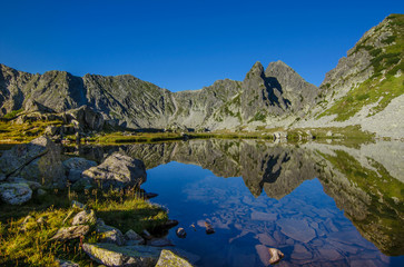 Fototapeta premium Mountain landscape and glacial Taul Portii lake in Retezat National Park, Carpathian Mountains, Romania, at sunrise