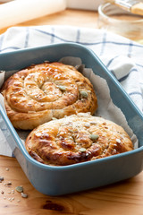 Freshly baked buns with sesame seeds in a baking tray on a wooden table.  