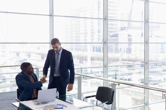 Two businessmen shaking hands in office - Powered by Adobe