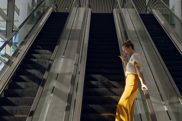 Businesswoman using smartphone on escalator