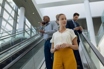 Young business people going down an escalator in a modern building