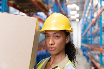 Female staff carrying cardboard boxes in warehouse