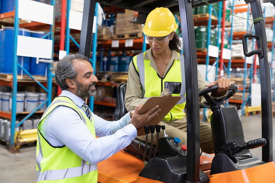 Male and female staff discussing over clipboard in warehouse