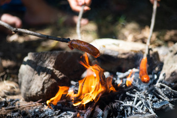 People baking sausage on fire on a picnic