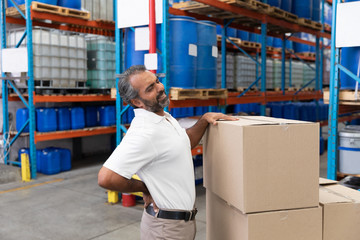 Male staff suffering from back pain while holding heavy cardboard box