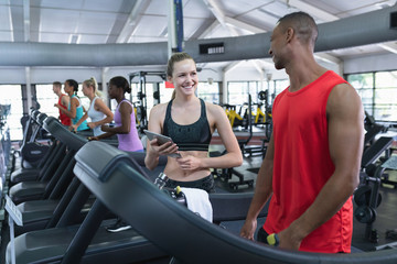 Obraz premium Female trainer assisting man to work out on treadmill