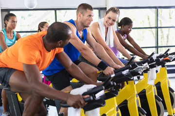 Fit people exercising on exercise bike in fitness center