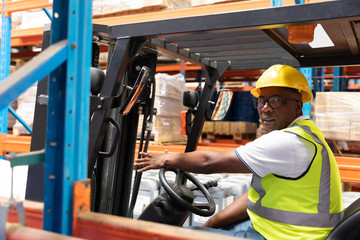 Male staff driving forklift in warehouse