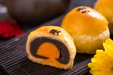 Tasty baked egg yolk pastry moon cake for Mid-Autumn Festival on black slate dark background. Chinese festive food concept, close up, copy space.