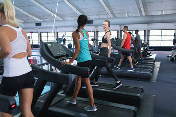 Fototapeta premium Fit woman interacting with her female friend while exercising on treadmill