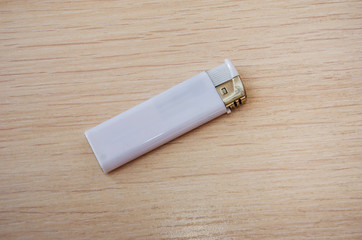 white lighter on a wooden background. View from above.