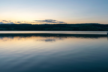 view of the lake at dawn early in the morning, silhouettes of hills and clouds