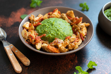 Mashed potatoes with green peas and corn served with chicken and vegetable stew. African cuisine, Kenyan cuisine, a traditional dish called mukimo or irio. Close-up