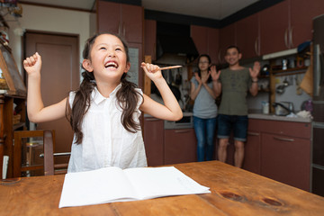 勉強をする女の子と見守る両親