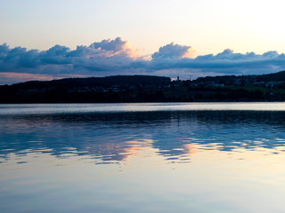 Fototapeta premium view of the lake at dawn early in the morning, silhouettes of hills and clouds
