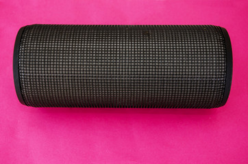 bluetooth column on a red background. Black, portable speaker isolated on red. Close-up.
