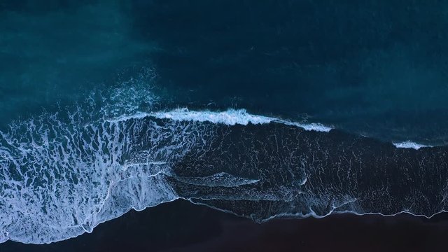 Top view of the desert black beach on the Atlantic Ocean. Coast of the island of Tenerife. Aerial drone footage of sea waves reaching shore