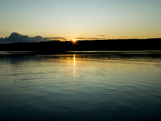 early morning on the lake, dusk, sun rising behind the hill